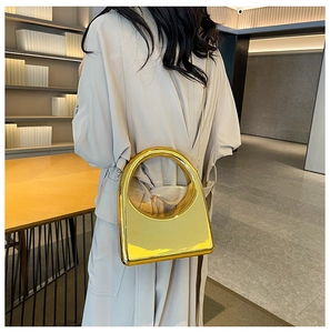 Close-up of golden mirror acrylic evening bag with metal ring handle and chain strap
