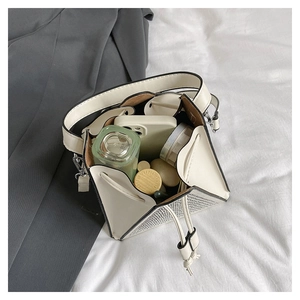 Détail d'un sac seau crème à paillettes argentées montrant l'intérieur et les objets