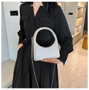 Silver metallic evening bag with mirror finish shown on a black dress background