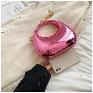 Detailed view of pink metallic heart-shaped bag with gold chain on textured fabric