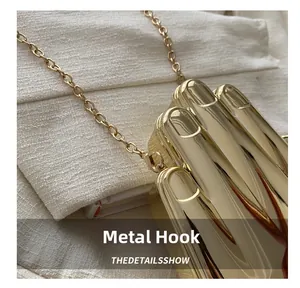 Detail of gold hand-shaped acrylic evening bag with metallic chain and glossy finish