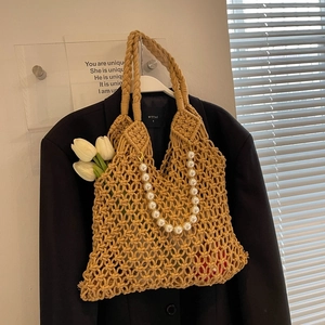 Detail of hollow mesh tote bag with large white pearl handle and woven texture detail