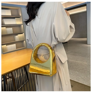 Detail of gold glossy metallic evening bag with large round handle and chain strap