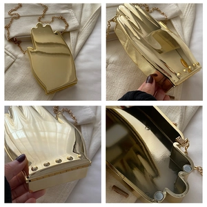 Macro detail of gold palm-shaped acrylic clutch with metallic chain and magnetic closure