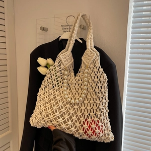 Detail of hollow mesh woven bag with luxury pearl handle and cotton rope texture