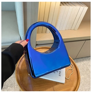 Close-up of electric blue acrylic clutch bag with a circular handle on a wooden tray
