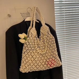 Detail of cream hollow mesh crochet tote bag with decorative oversized pearl chain strap
