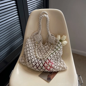 Detail of hollow woven macrame bag with pearl handle and wide shoulder strap
