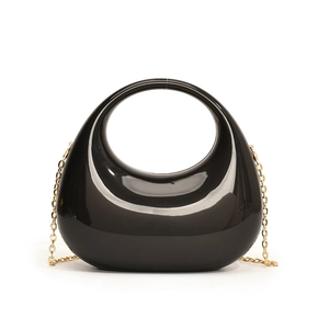 Detail of black acrylic crescent handbag with gold chain strap and glossy round handle