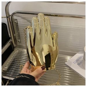 Detail of creative gold hand-shaped acrylic evening bag with mirror finish and chain strap