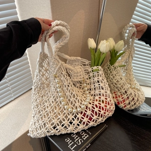 Detail of white macrame woven beach bag with pearl chain and tulip decoration
