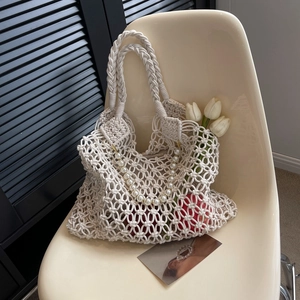 Detail of macramé woven beach bag with crochet mesh pattern and faux pearl strap decoration