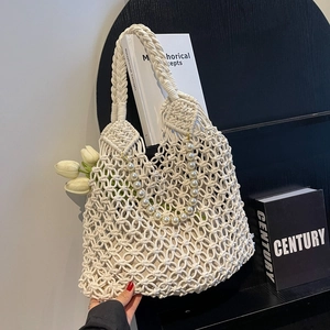Detail of macramé beach bag featuring pearl handle, mesh knit pattern and wide shoulder strap