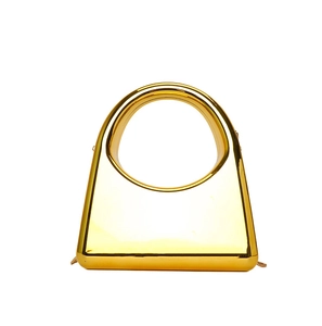 Detail of a geometric gold acrylic clutch bag with a large round hollow top handle