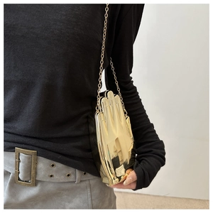 Detail of creative gold hand-shaped acrylic clutch bag with delicate metal chain strap
