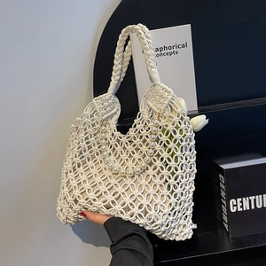 Detail of white hand-woven mesh beach bag featuring large pearl chain and sturdy handle