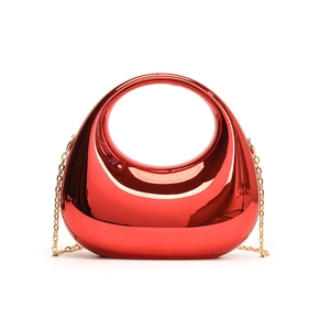 Detail of red acrylic box bag featuring round cutout handle and gold chain strap