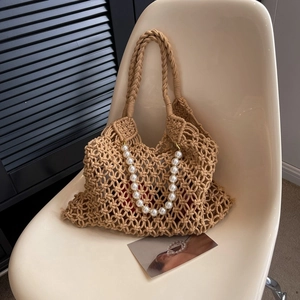 Detail of hollow mesh woven bag with pearl chain and red inner lining on a white chair
