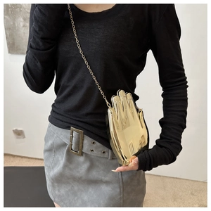 Detailed view of a gold palm-shaped acrylic clutch with a metallic chain strap