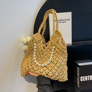 Detail of woven mesh beach bag featuring large pearl embellishments and sturdy handles