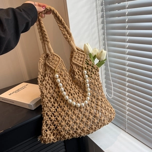 Detail of hollow mesh woven beach bag with white pearl chain and cotton lining