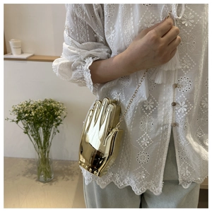 Artistic gold hand-shaped acrylic clutch with metallic chain and spherical rivets