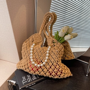 Close-up of khaki woven mesh tote bag with luxury pearl handle on a wooden table