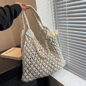Detail of white crochet mesh beach bag with pearl chain handle and tulip flower accents