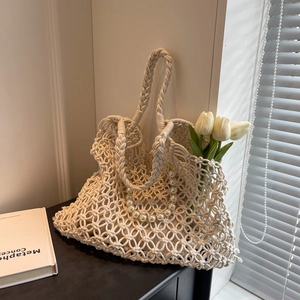 Detail view of cream woven hollow mesh beach bag with large pearl handle and braided straps