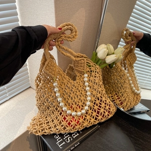 Detail of hollow woven beach bag with pearl handles and elegant beige mesh texture