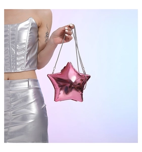 Detail view of pink metallic star-shaped crossbody bag with silver chain strap on model