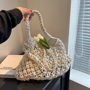 Close-up of white woven mesh beach bag featuring large pearls and sturdy braided handles