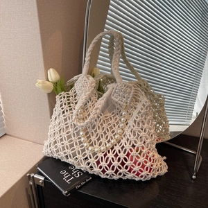 Detail of white macrame tote bag with pearl handle and intricate hollow weave pattern