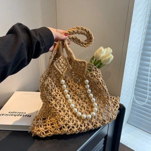 Detail of beige mesh woven beach bag with decorative white pearl chain strap and tulips