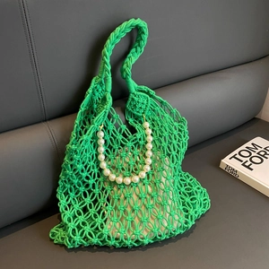 Detail of green crochet hollow mesh bag with white inner pouch and pearl handle ornament