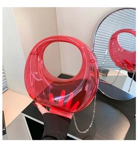 Close-up of transparent red acrylic crescent bag with silver chain and modern round design
