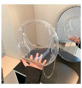 Detail view of transparent acrylic evening bag with round handle and metal chain strap