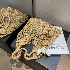 Close-up of woven mesh handbag featuring large pearl handle and beige lining on display
