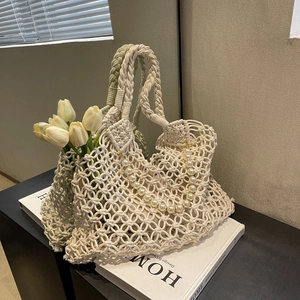 Close-up of cream woven mesh beach bag with decorative pearls and floral detail