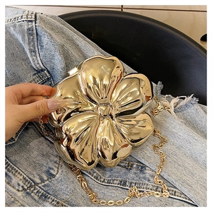 Detailed close-up of golden flower evening clutch with 3D petals and chain strap
