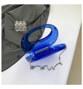 Detail of blue acrylic crescent handbag with silver metal chain and integrated handle