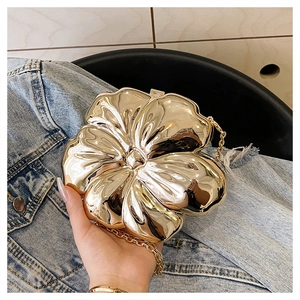 Close-up of golden flower-shaped evening clutch with mirrored finish and metal chain