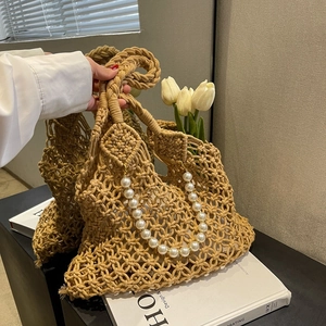 Detail of hollow-out mesh woven beach bag with pearl chain and thick braided handle