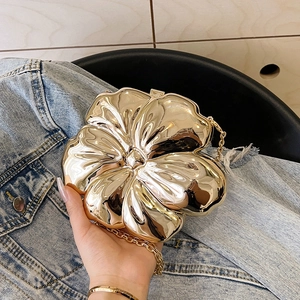 Detail of flower-shaped evening clutch in polished gold metal finish with chain strap