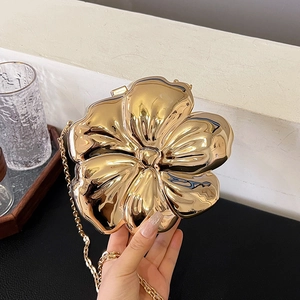 Detailed close-up of golden floral metal evening bag with glossy mirror finish and chain