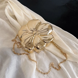 Detail of flower-shaped evening clutch featuring metallic gold finish and crossbody chain