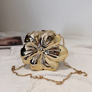 Detailed view of flower-shaped evening clutch bag in gold finish with metal chain strap