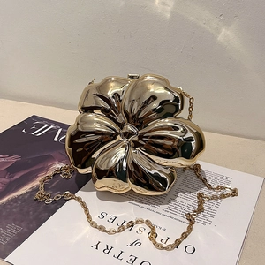 Macro detail of gold flower evening bag with shiny metallic finish and chain strap