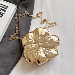 Detail shot of golden floral clutch bag with shiny metal finish and elegant chain