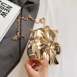 Detail of golden floral evening clutch featuring 3D petals and metallic chain strap